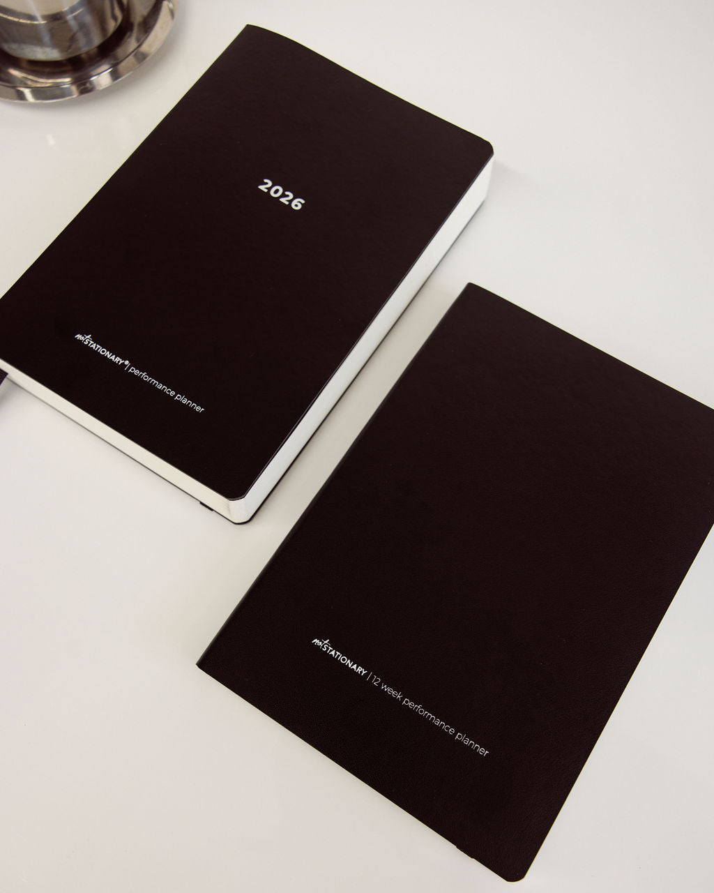 Two black planners with '2023' on the cover on a white surface.