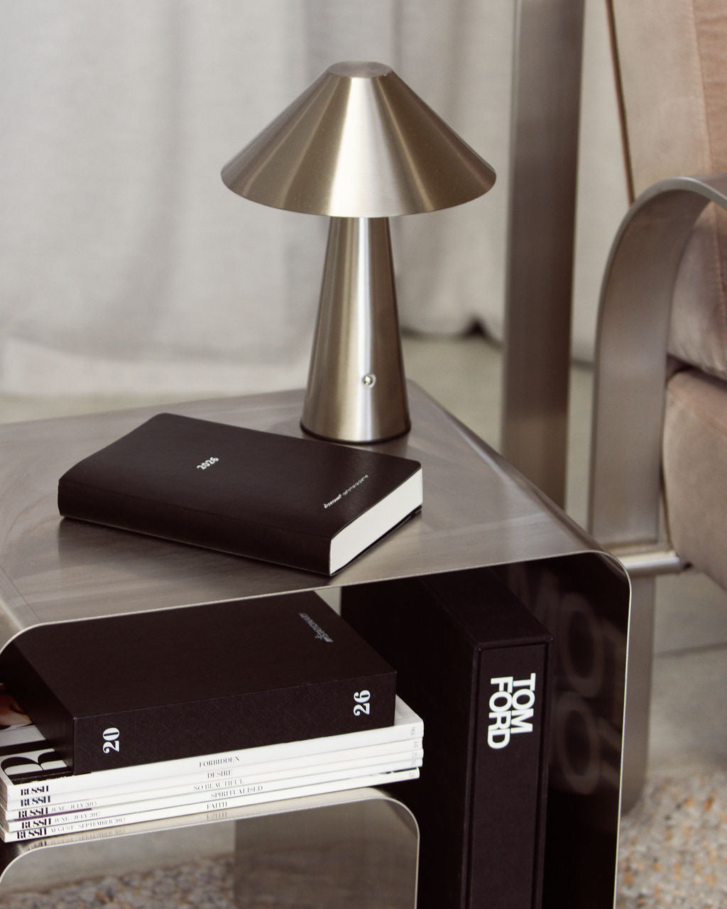 Minimalist black 2026 Not Stationary Performance Planners styled on a modern side table with a Tom Ford book, design magazines, and a sleek silver lamp.