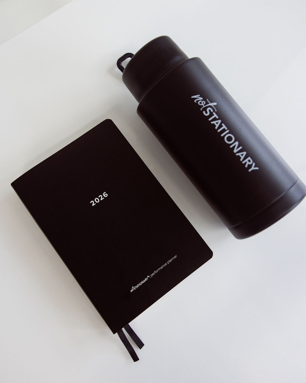 Black notebook and thermos drink bottle with 'notSTATIONARY' branding on a white background