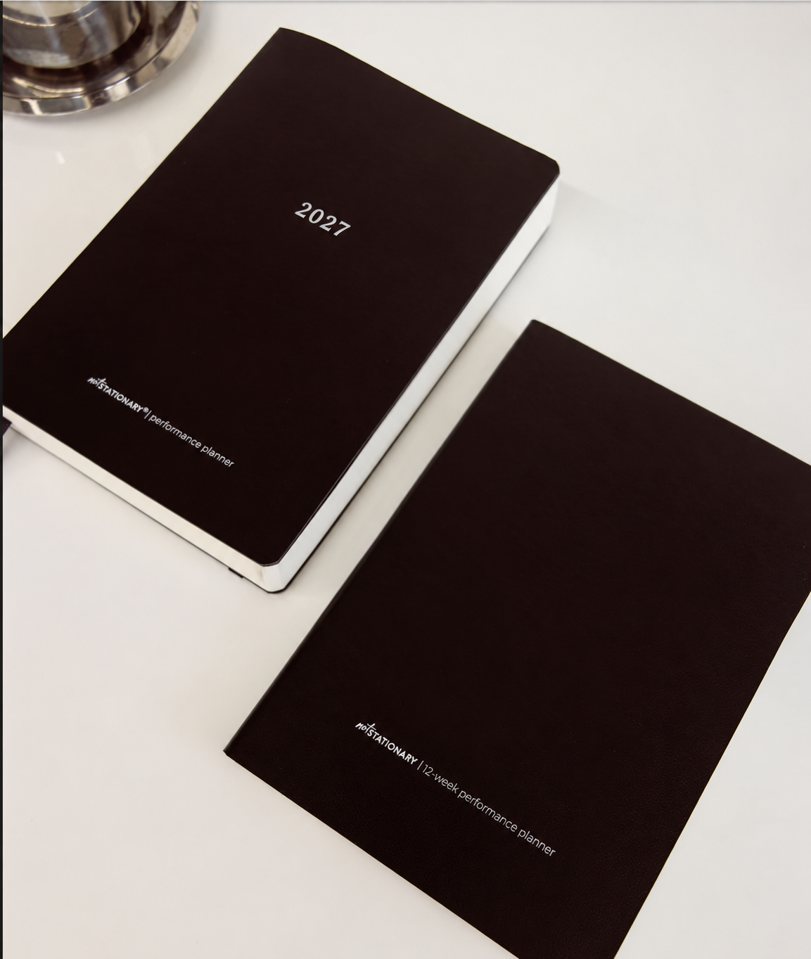 Two black 2027 performance planners by not stationary on a clean white surface
