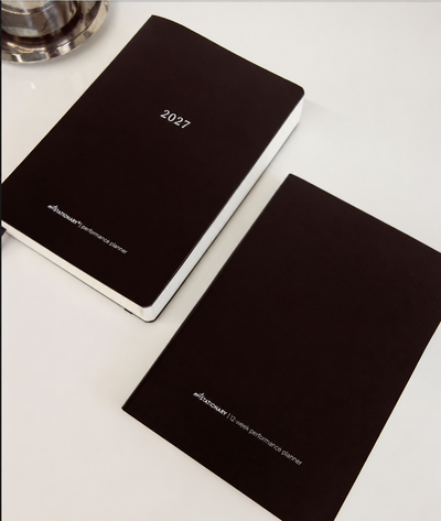 Two black 2027 performance planners by not stationary on a clean white surface