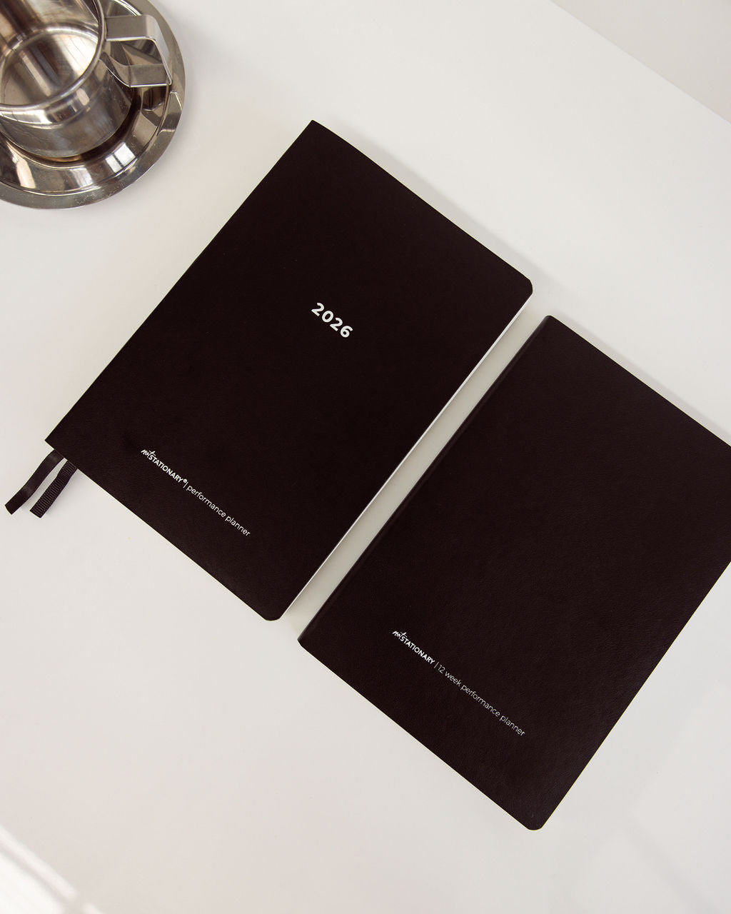 Two black diaries with '2026' printed on them, placed on a white surface.