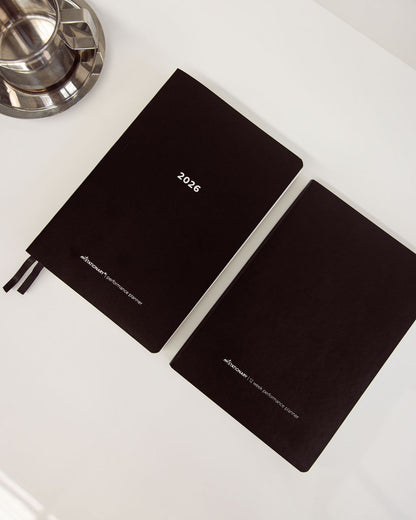 Two black diaries with '2026' printed on them, placed on a white surface.