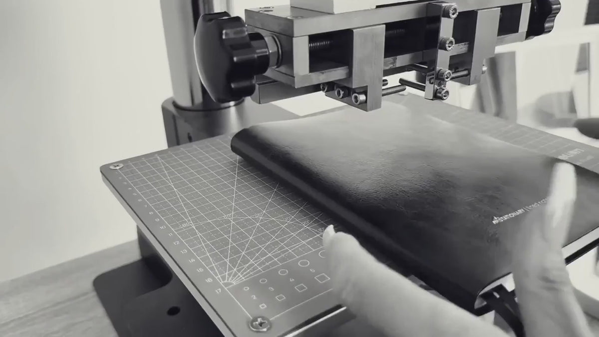 Load video: Close-up of Not Stationary planner being monogrammed with custom initials using a heat press.